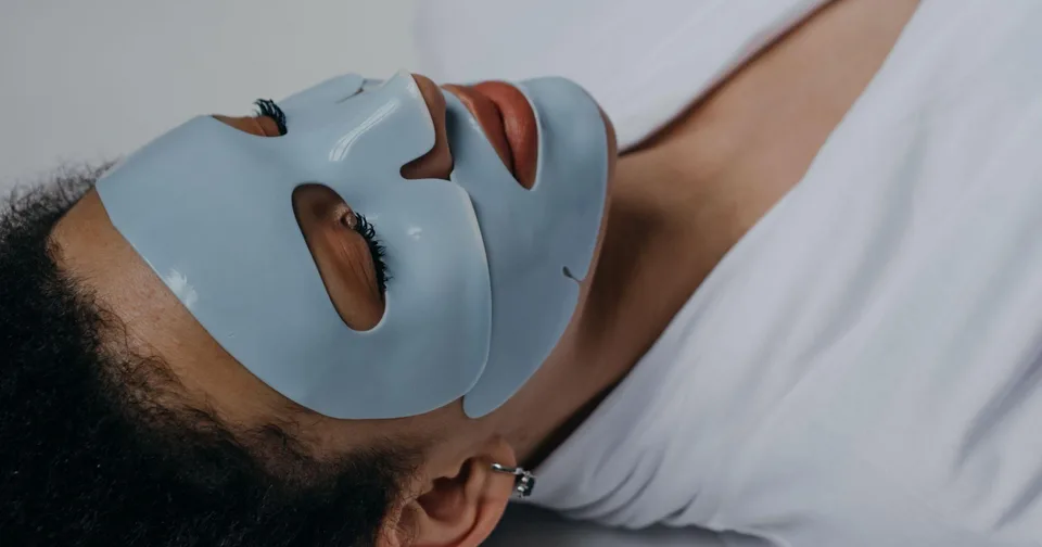 Osoba se světle modrou plátýnkovou maskou vleže na zádech