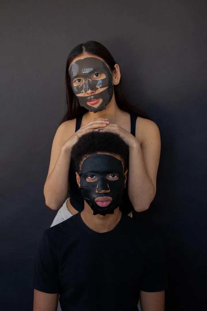 Dvě osoby s plátýnkovými maskami na tmavém pozadí